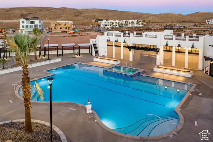 Expansive pool area featuring multiple swimming sections, an integrated spa with water features, and surrounding concrete decking