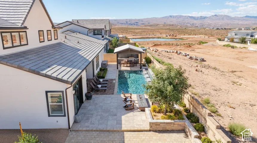 Expansive backyard featuring a rectangular swimming pool, an outdoor covered lounge area, and paver patio
