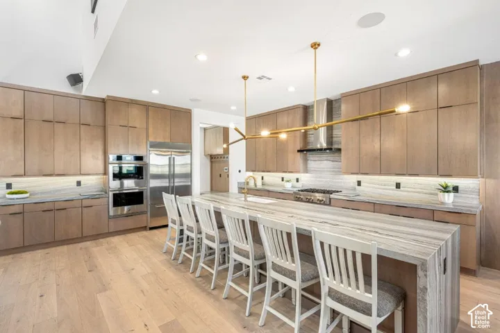 Spacious kitchen featuring light wood-finish cabinetry, stainless steel appliances, and a large central island with a matching countertop