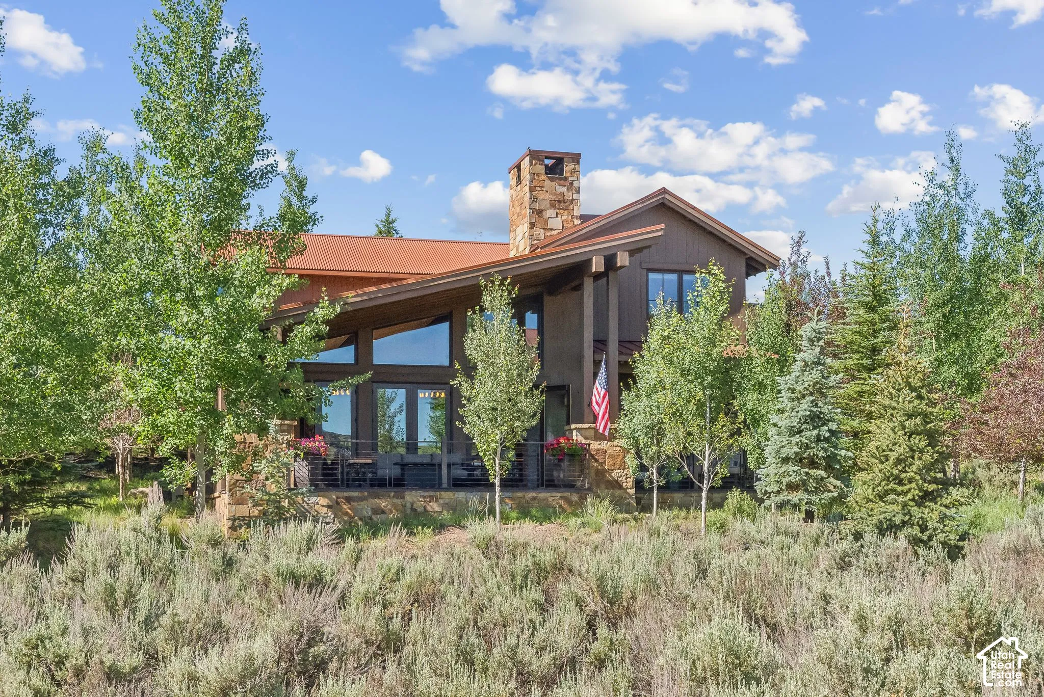 Mountain-style architecture featuring a stone chimney and expansive windows