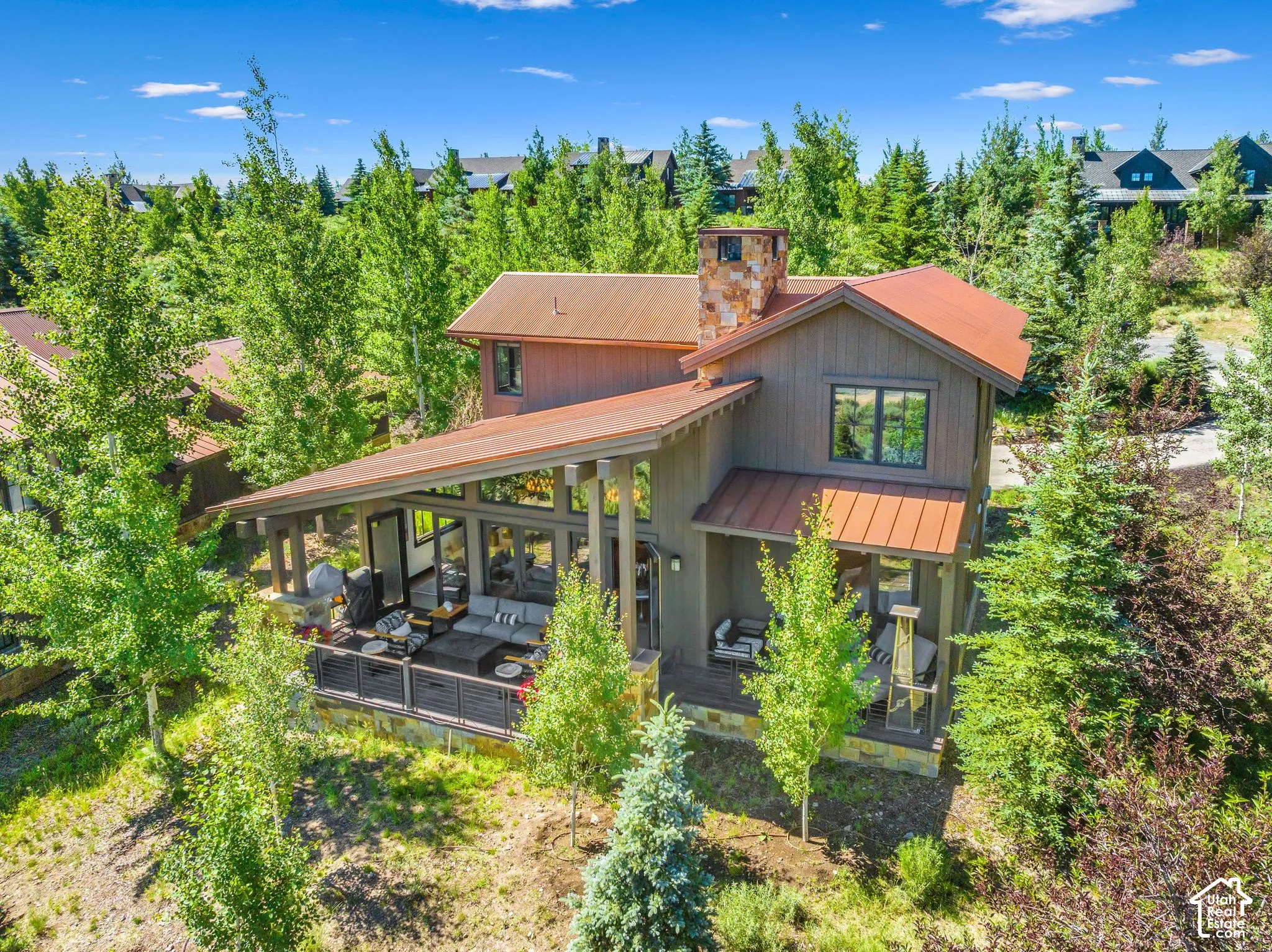 Two-story exterior with a metal roof, stone chimney, and wood siding