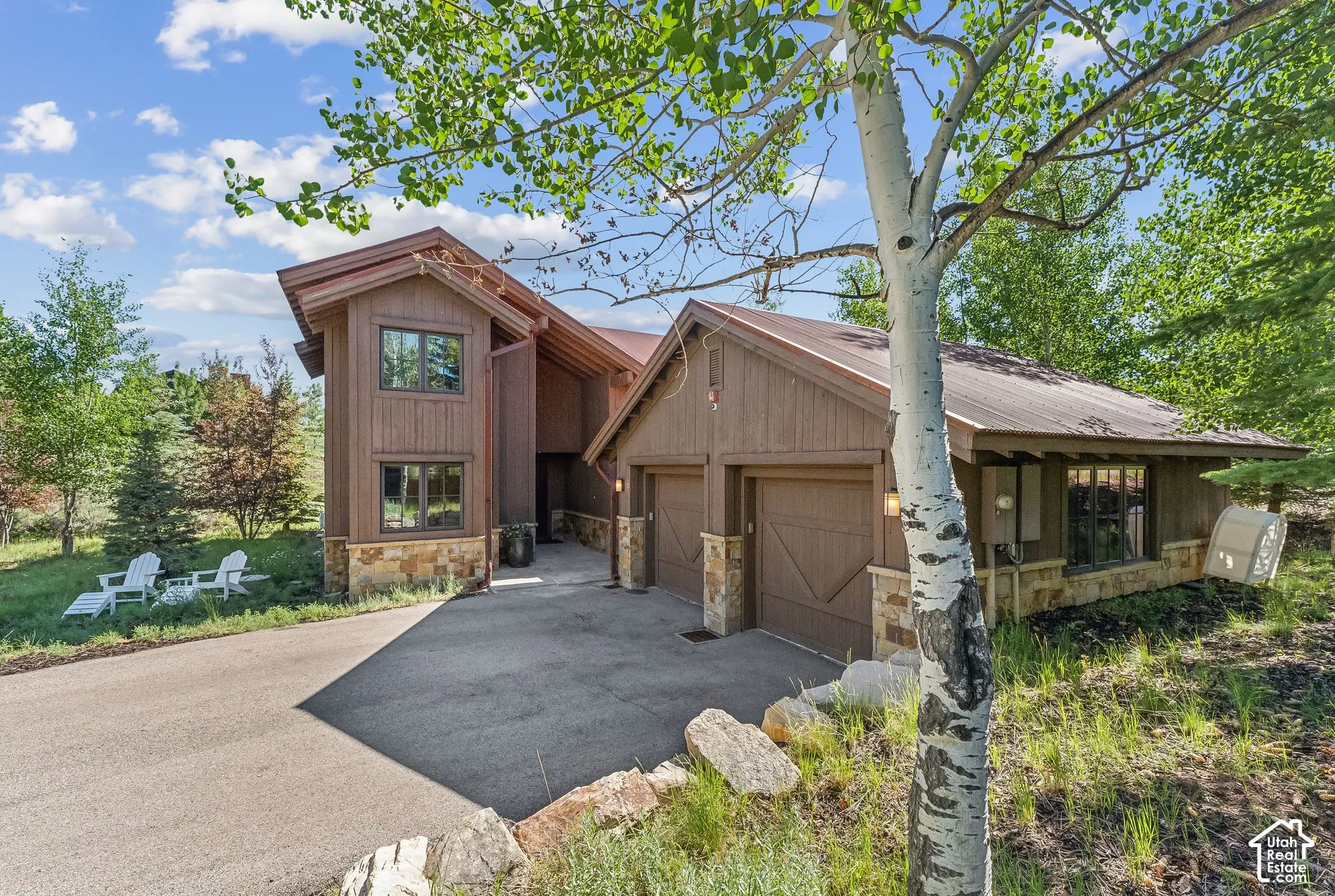 Custom-built exterior featuring wood siding, stone accents, a metal roof, and an attached two-car garage