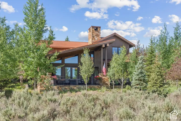 Mountain-style architecture featuring a stone chimney and expansive windows
