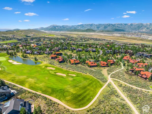 Aerial view showcasing an 18-hole championship golf course with manicured fairways, strategic bunkers, and a water feature, set within a residential community surrounded by mature landscaping