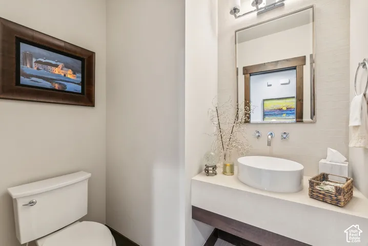 Modern powder room featuring a circular vessel sink with a polished countertop, framed mirror with integrated lighting, and subway tile wall finish