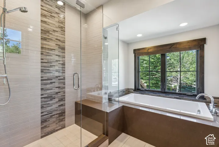 Glass-enclosed shower with mosaic tile accent and integrated bench