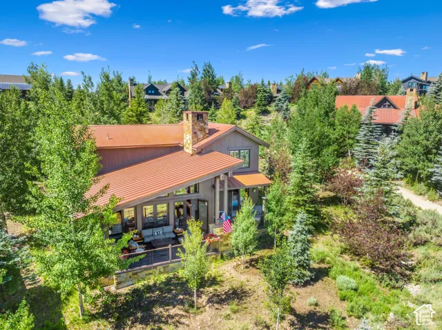 Angled metal roofline, stone chimney, and expansive outdoor deck with railing