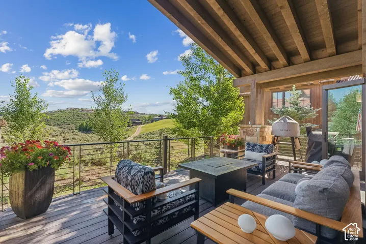 Expansive outdoor deck featuring wood-finish flooring, a cable railing system, and a built-in fire pit