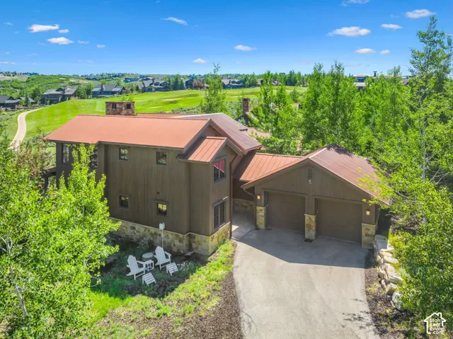 Wood-paneled exterior with a metal roof, stone foundation, and a two-car garage