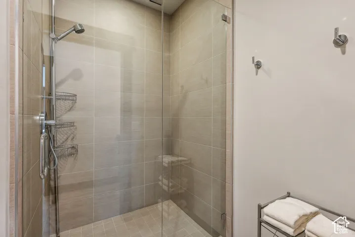 Glass-enclosed shower with full-height tile surround, integrated showerhead, and wall-mounted hooks