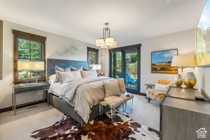 Hardwood flooring, wood window trim, sliding glass doors, built-in headboard, and a multi-bulb ceiling fixture