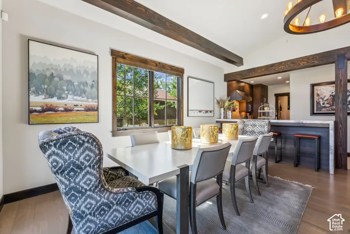 Dining area featuring exposed wood-finish ceiling beams, wood-finish flooring, and a large window with wood-finish trim