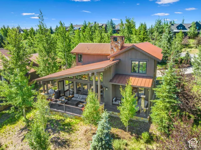 Two-story exterior with a metal roof, stone chimney, and wood siding