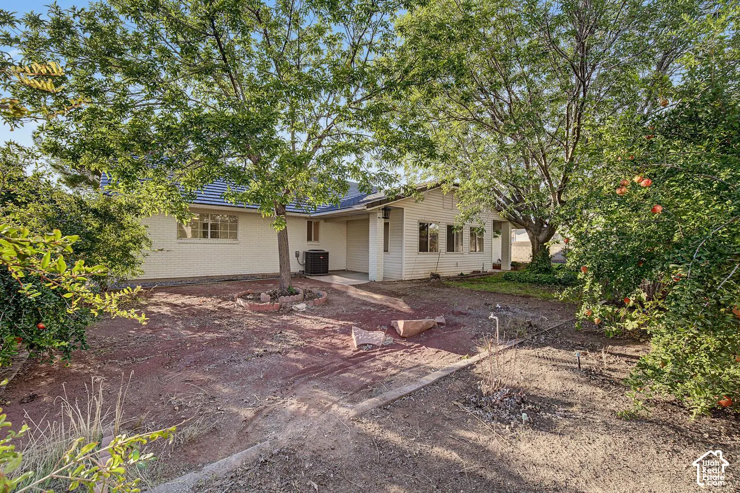 Exterior featuring a covered patio, multiple windows, and mature trees