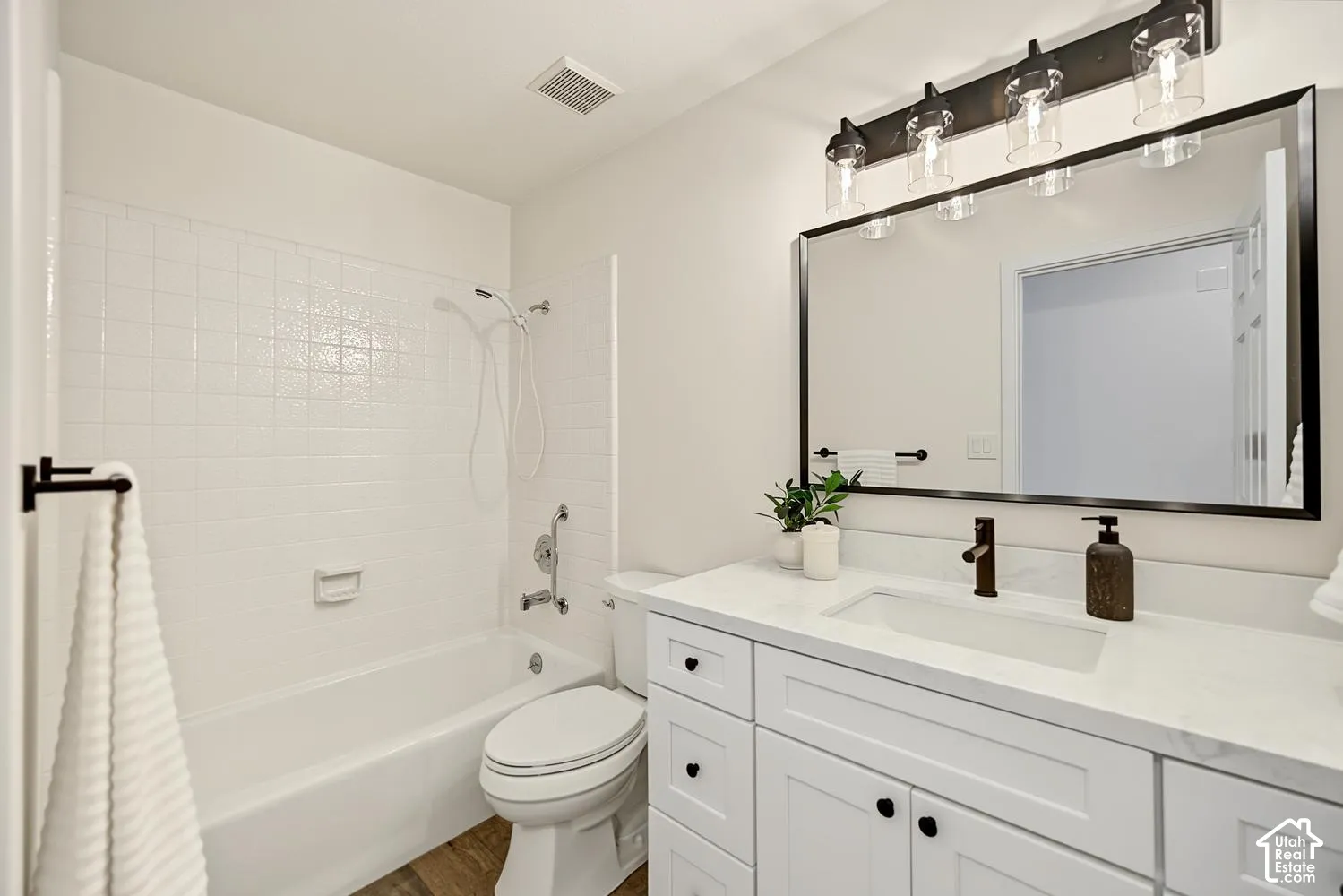 White vanity with under-mount sink, quartz countertop, and dark bronze faucet