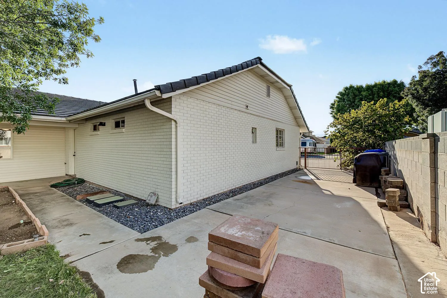 Brick exterior with a dark-tiled roof, concrete pathways, and a block wall perimeter