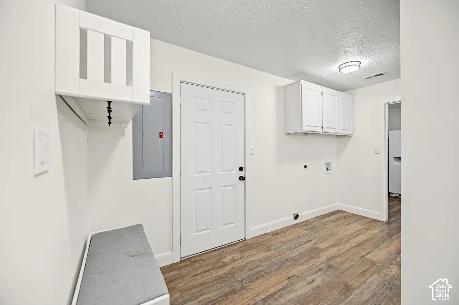 Wood-finish flooring, white paneled door, built-in white cabinetry, modern flush mount ceiling light, and built-in bench seating
