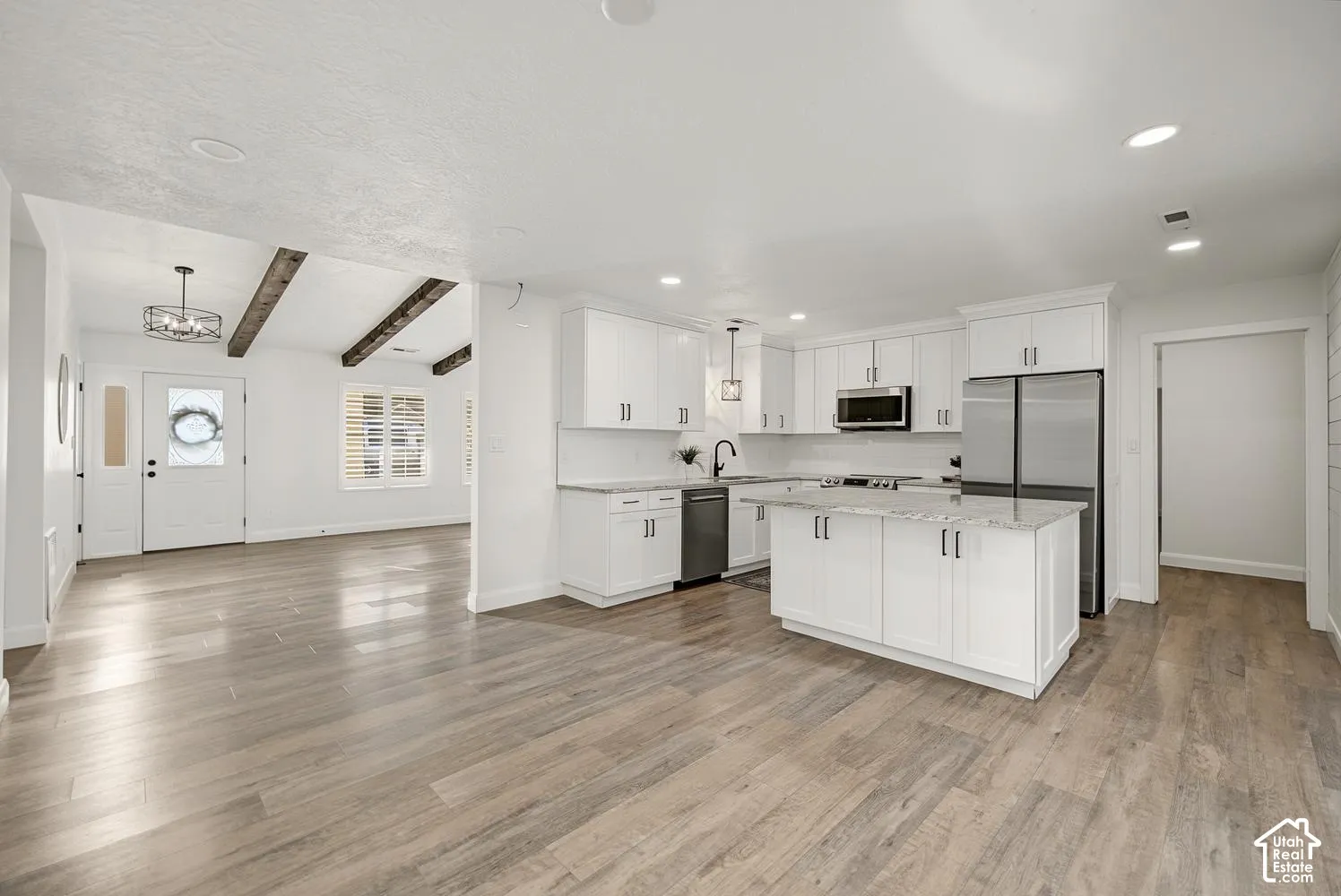 Modern kitchen with white cabinetry, stainless steel appliances, and a central island