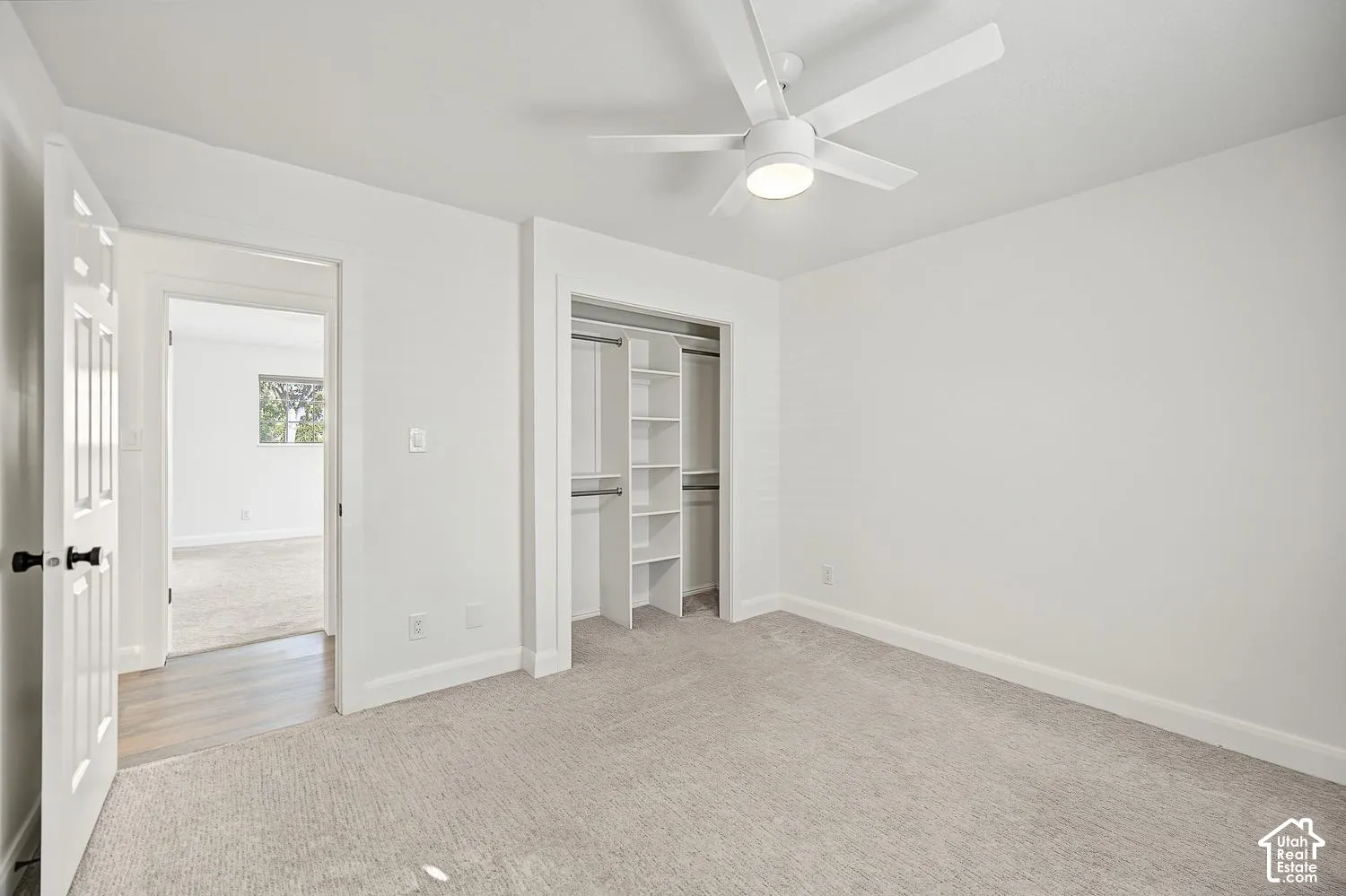 Neutral-toned carpeting, ceiling fan with integrated lighting, built-in closet shelving, and a paneled interior door