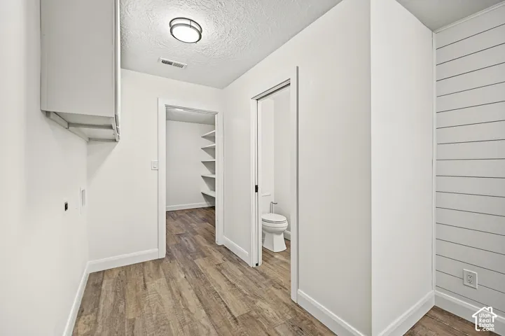 Wood-finish flooring throughout, white upper cabinetry, and a ceiling-mounted light fixture