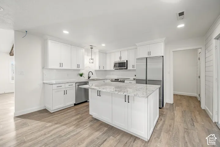 Kitchen featuring white shaker-style cabinetry, granite countertops, stainless steel appliances, wood-finish flooring, and recessed lighting