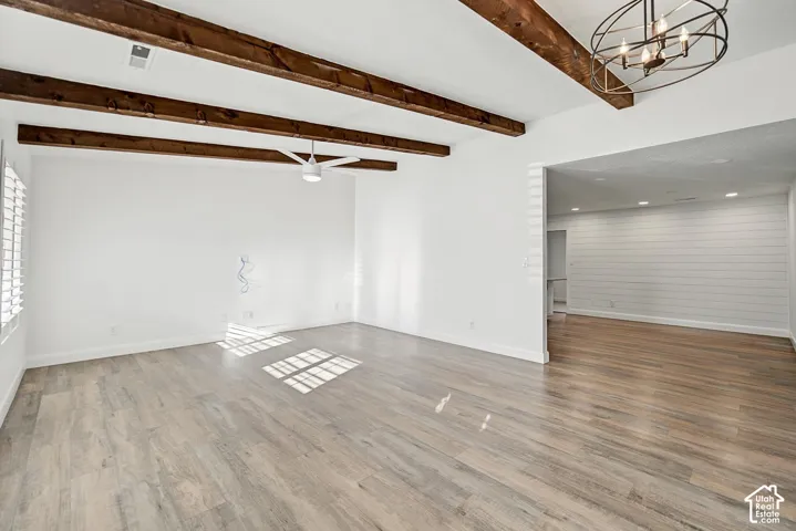 Exposed ceiling beams, wood-finish flooring, white walls, and a modern ceiling fan