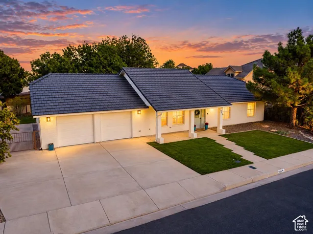 Contemporary ranch-style residence featuring a dark-tiled roof, white exterior, and a three-car garage