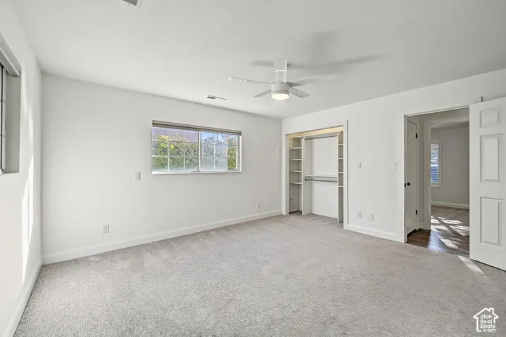 Wall-to-wall carpeting, two windows, ceiling fan, and built-in closet shelving