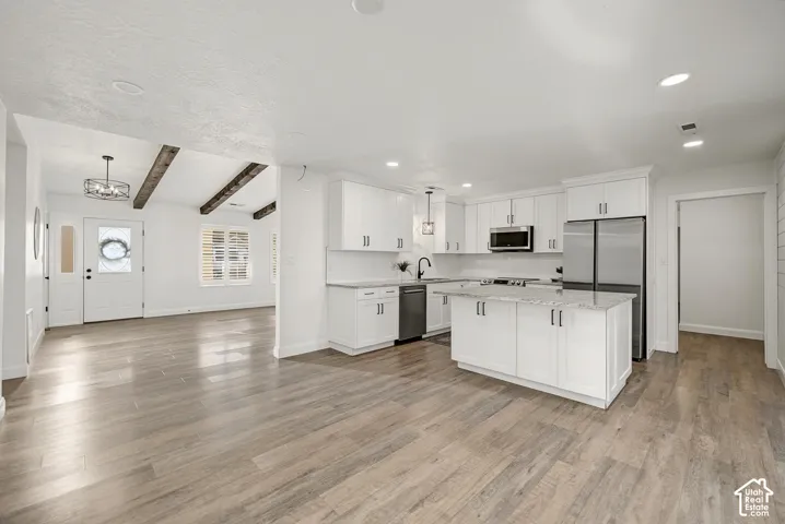 Modern kitchen with white cabinetry, stainless steel appliances, and a central island