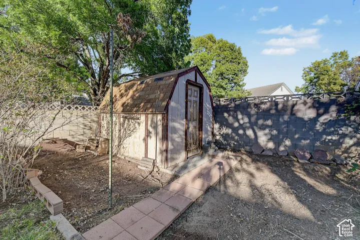 Charming backyard retreat featuring a peaked-roof storage shed with arched doorway and dual-pane windows