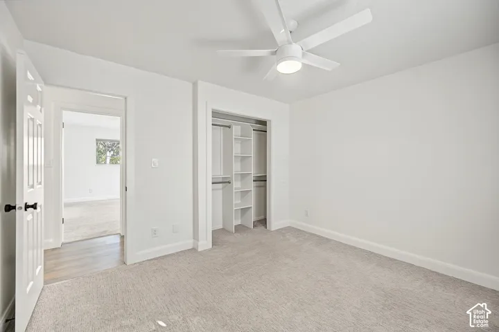 Neutral-toned carpeting, ceiling fan with integrated lighting, built-in closet shelving, and a paneled interior door