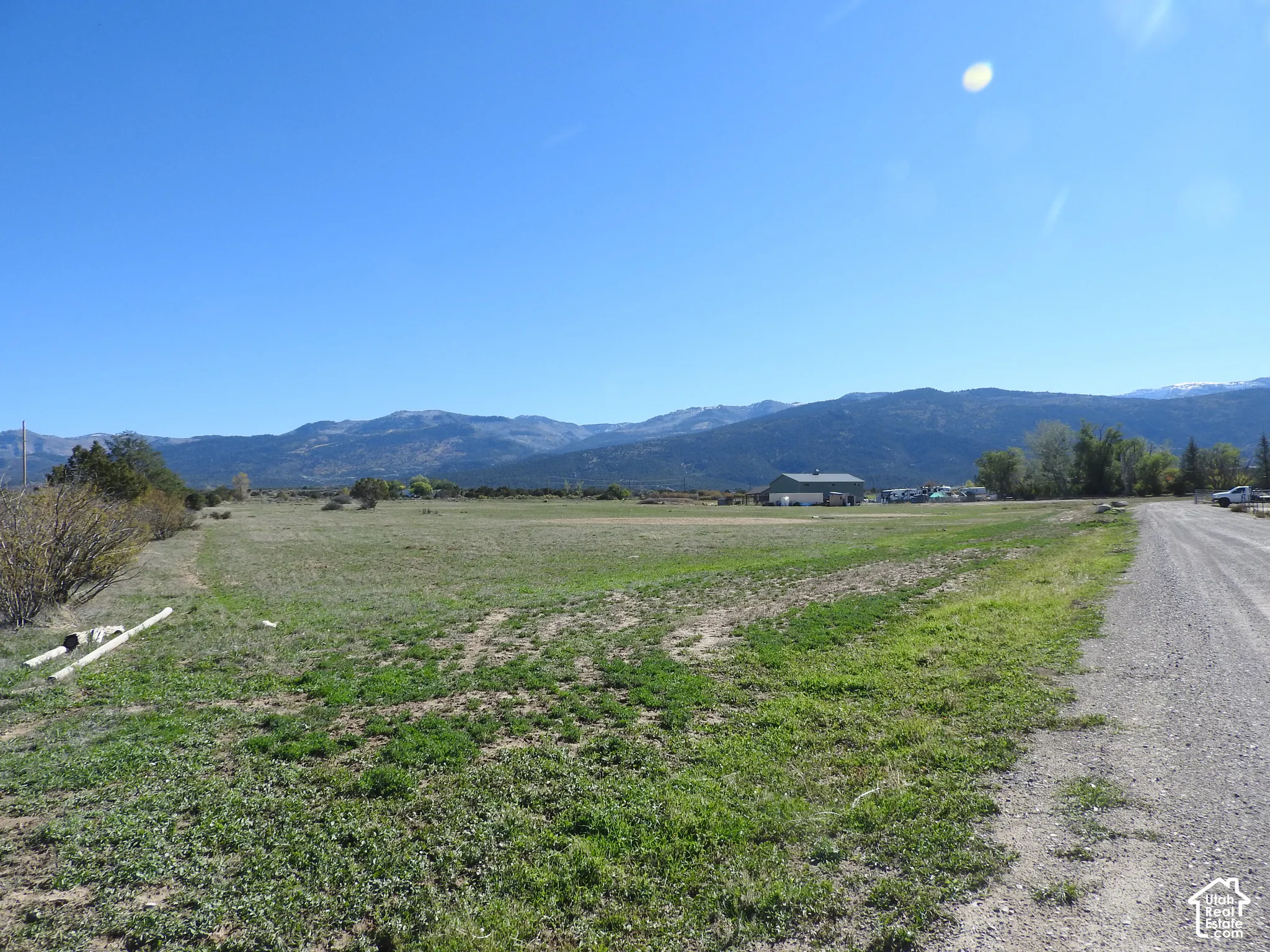 Expansive open terrain featuring mountain backdrops, native grasses, and gravel road access