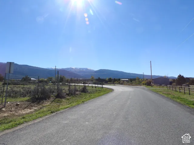 Paved roadway featuring expansive mountain backdrops and open rural terrain
