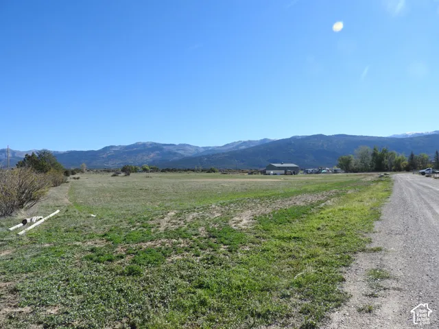 Expansive open terrain featuring mountain backdrops, native grasses, and gravel road access