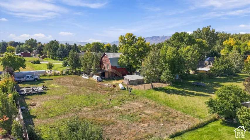 Expansive property featuring a red barn, mature trees, and a distant mountain backdrop