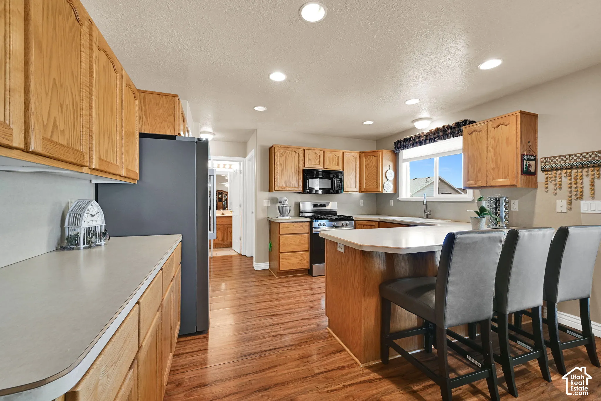 Kitchen featuring wood-finish flooring, recessed lighting, wood cabinetry, and an island with counter seating