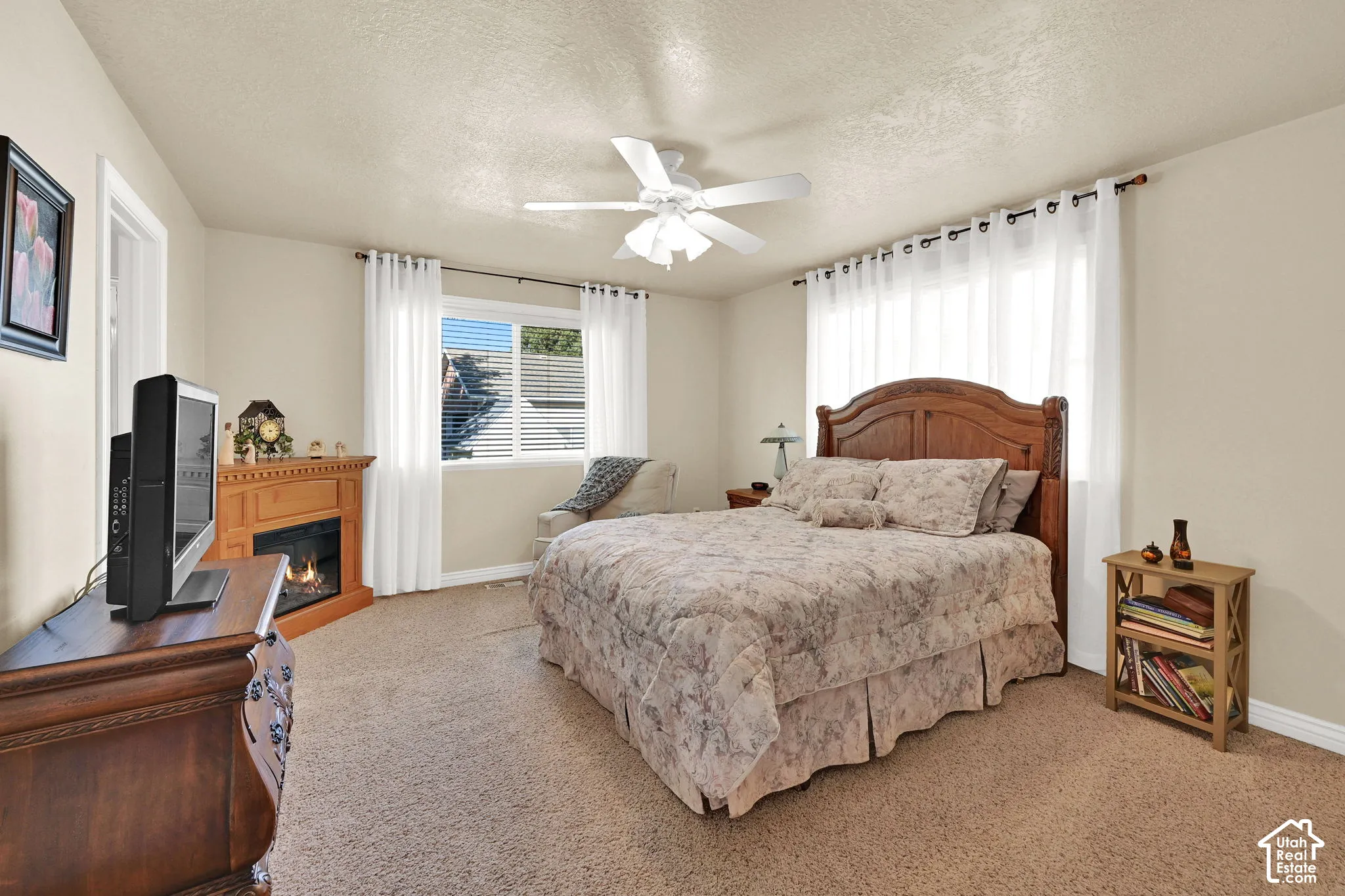 Recessed lighting, wood-finish fireplace surround, large window with blinds, ceiling fan, and carpeted flooring
