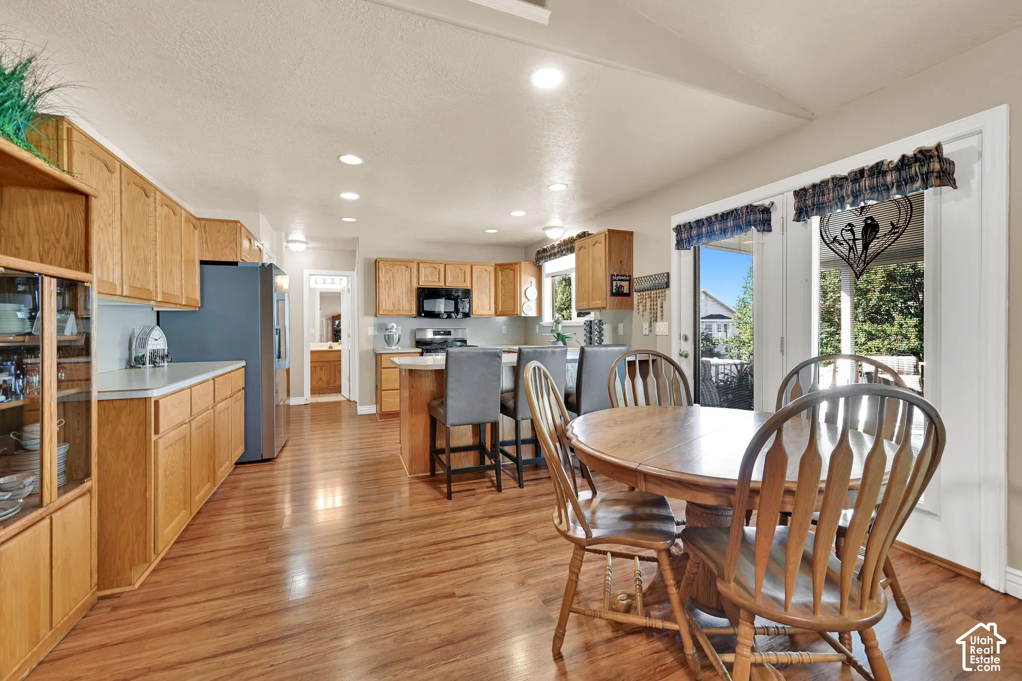 Wood-finish flooring, ample cabinetry, recessed lighting, and a glass-front display cabinet