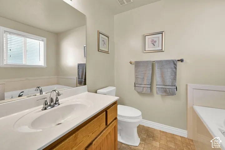 Built-in bathtub with tiled surround, wood-finish vanity, and integrated sink