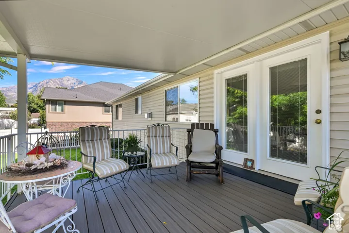 Covered outdoor deck with composite decking and white metal railings, featuring double glass-paneled doors and siding exterior