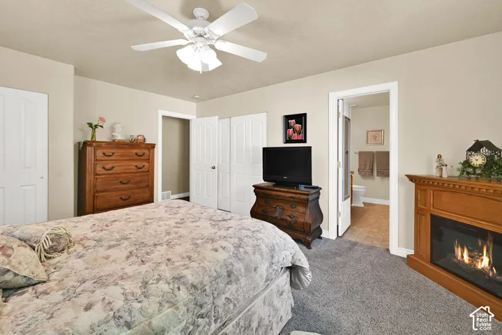 Recessed fireplace with wood-finish mantel, ceiling fan with light fixture, carpeted flooring, and a solid core interior door