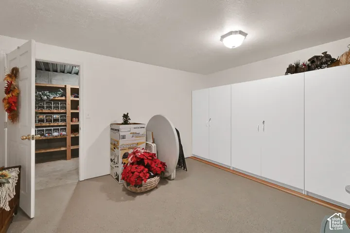 Full-height white cabinetry with a light-colored baseboard, recessed ceiling lighting, and a separate storage room with wooden shelving