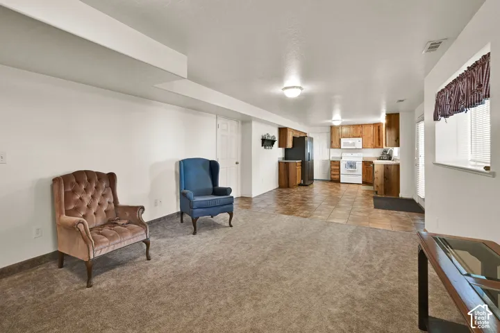 Expansive open-concept space featuring carpet flooring, tile flooring, wood cabinetry, and white appliances