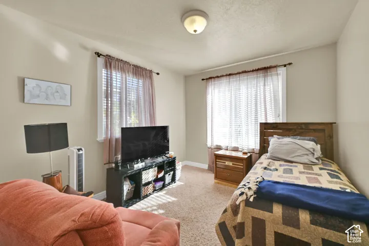 Recessed lighting, wood-finish headboard, window with blinds, carpeted flooring, and neutral wall tones