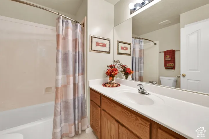 Full bathroom featuring a white tub/shower combination, extensive vanity with integrated sink, and an expansive mirror