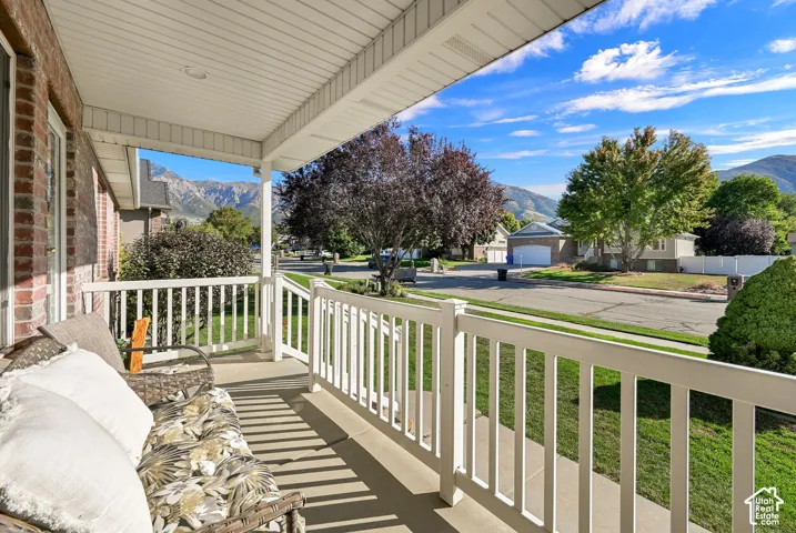 Covered front porch with white railings, brick facade, and recessed lighting