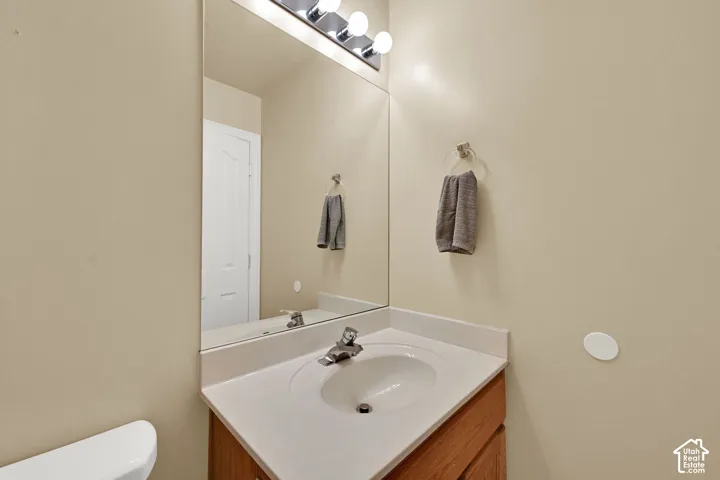 Vanity with an integrated sink, polished chrome faucet, wood-finish cabinetry, and a large wall mirror