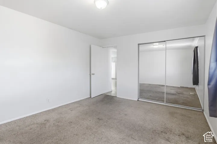 Neutral-toned carpeted flooring complements light-colored walls and a ceiling-mounted light fixture