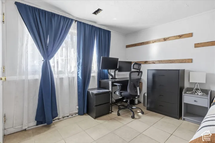 Tiled flooring, white wall finishes, and a single window with curtain rods