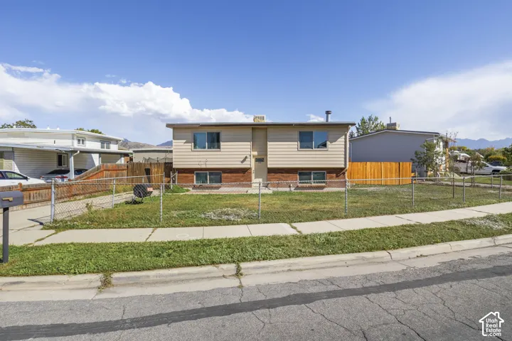 Split-level residence featuring tan siding and a brick-finish lower level